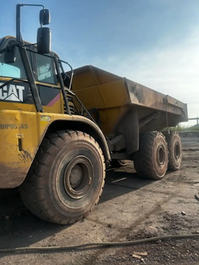 An articulated haul truck caked in mud before washing